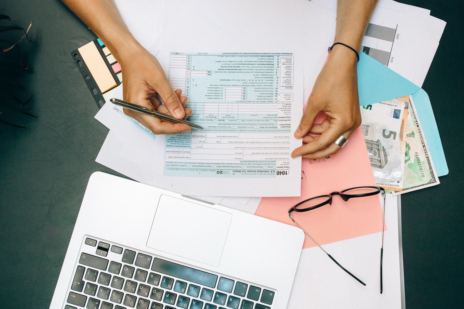 A desk with a laptop and printed tax forms