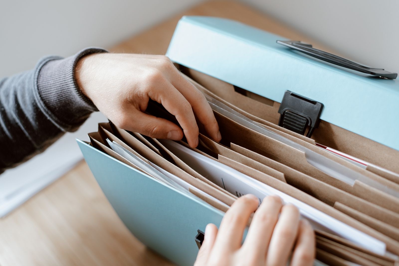 Hands sorting folders of corporate documents on a desk