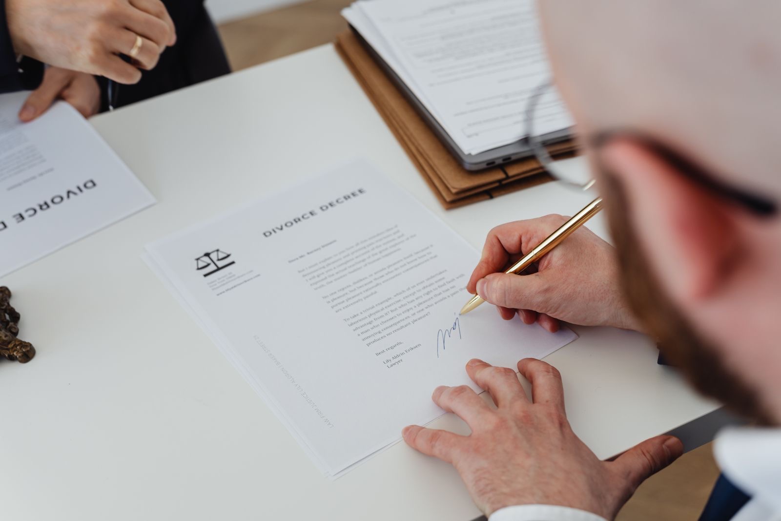 Hands signing a contract at a wooden desk