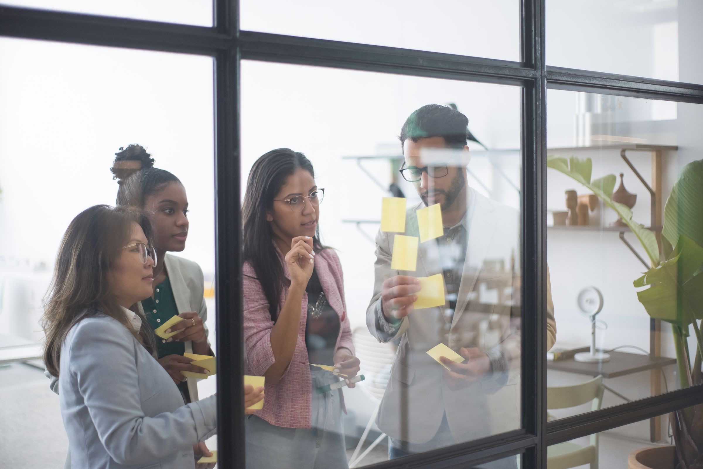 Colleagues around a table in a glass-walled office reviewing company documents